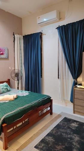 a bedroom with a bed with blue curtains at MQ Homestay in Temerloh