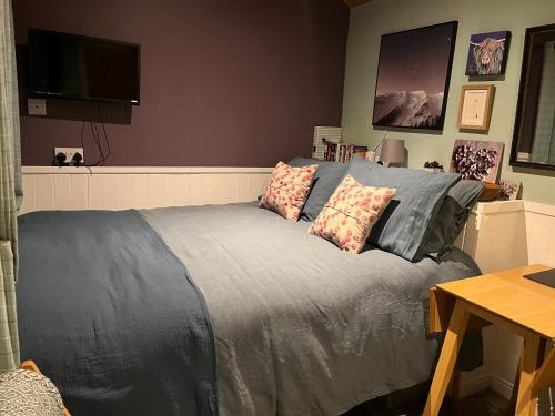 a bedroom with a bed and a flat screen tv at The Aultnamain Shepherds Hut in Wester Fearn