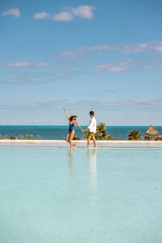 a man and a woman walking on a beach at Secrets Playa Mujeres Golf & Spa Resort - All Inclusive Adults Only in Cancún
