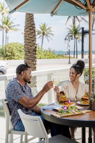 a man and woman sitting at a table with a glass of wine at Sonesta Fort Lauderdale Beach in Fort Lauderdale