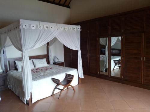 a bedroom with a canopy bed and a chair at Villa Elina in Lovina