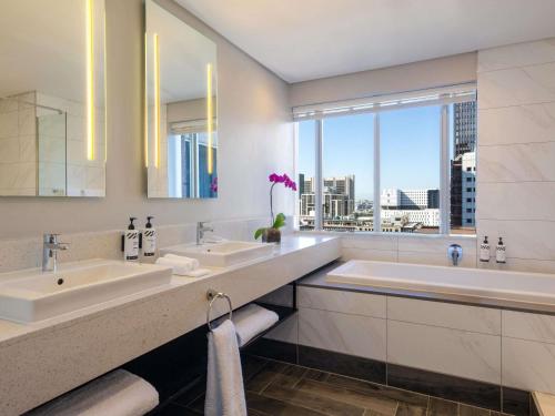 a bathroom with two sinks and a large window at Pullman Cape Town City Centre in Cape Town
