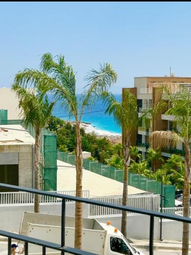 a view of the beach and palm trees from a balcony at Santorini Village, Drymades, Dhermi in Dhërmi