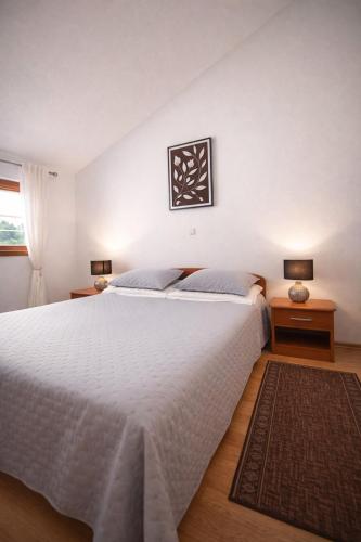 a bedroom with a large white bed and two lamps at Apartment Tina in Obrovac