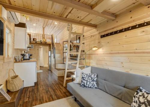 a living room with a gray couch in a tiny house at Red Rock Roost Posh Studio near Hiking Trails in Colorado Springs