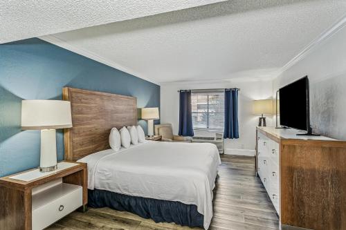 a bedroom with a large bed and a television at At Home Inn - Pensacola in Pensacola