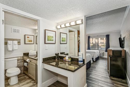 a hotel room with a bathroom with a bed and a toilet at At Home Inn - Pensacola in Pensacola