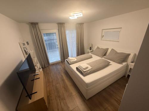 a bedroom with a white bed and a television at Samaria Apartments in Šamorín