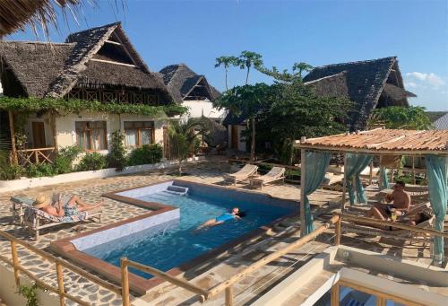 a pool at a resort with people swimming in it at ZANZIBAR TROPICAL SUNSET - Adults Only Boutique Hotel by Sofia Collection in Kiwengwa