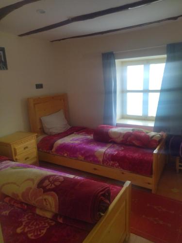 a bedroom with two beds and a window at Maison Ighrem in Idoukaln