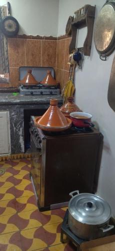 a kitchen with a stove with pots and pans on it at Maison Ighrem in Idoukaln