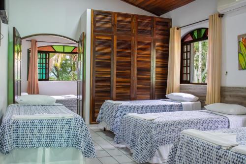 a room with three beds and two windows at Marencanto Pousada in Ubatuba