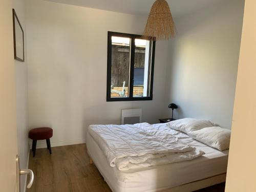 a bedroom with a white bed and a window at Le Moutchic in Lacanau