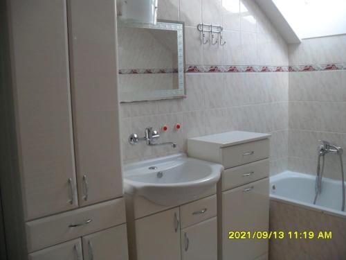 a white bathroom with a sink and a tub at Apartmány Prima-Pokoje in Mimoň