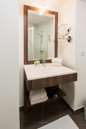 a bathroom with a sink and a mirror at Ténéo Apparthotel Talence Espeleta - Bordeaux Sud in Talence