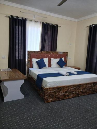 a bedroom with a large bed with blue pillows at Raj Hotel and Restaurant in Bhadarwāh