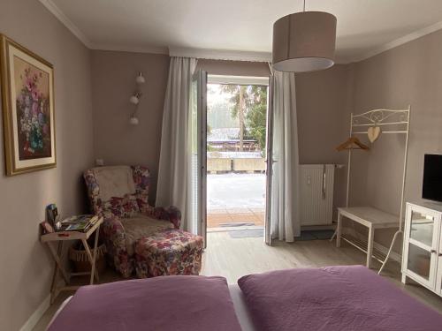 a bedroom with a bed and a chair and a sliding glass door at Apartment am Golfplatz in Obernkirchen