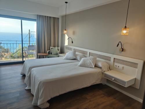 a bedroom with a large bed and a large window at Hostal Sa Baronia in Banyalbufar