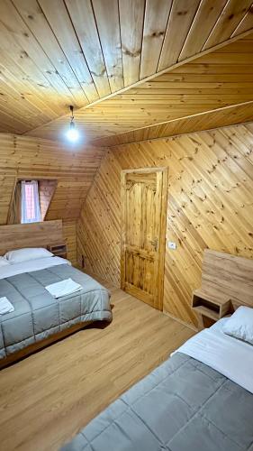 a room with two beds and a wooden ceiling at Bujtina Vellezerit Grrela in Theth