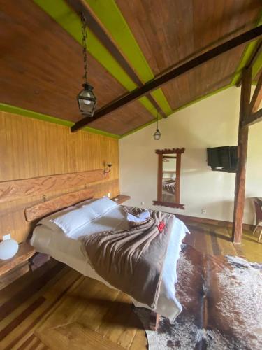 a large bed in a room with a wooden ceiling at Chalé Bougainville in Lavras Novas