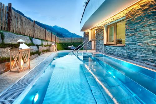 a swimming pool in a house with a stone wall at Grossarler Hof Superior in Grossarl