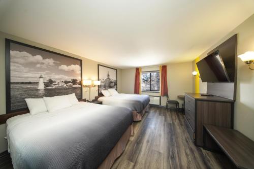 a hotel room with two beds and a flat screen tv at Super 8 by Wyndham Kingston in Kingston