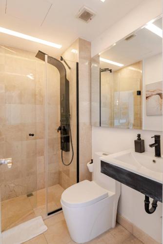 a bathroom with a shower and a toilet and a sink at Cana Rock Infinity Pool & Beach Club in Punta Cana