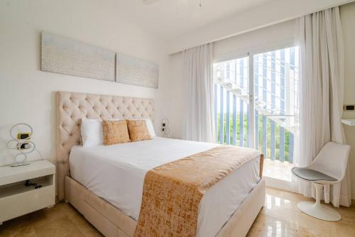 a white bedroom with a large bed and a window at Cana Rock Infinity Pool & Beach Club in Punta Cana