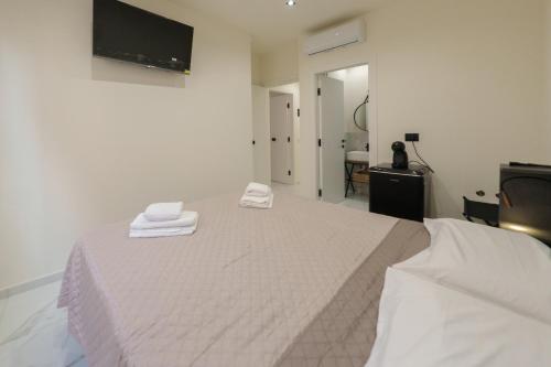 a white bed with two towels on top of it at Dimora Costa Cefalù in Cefalù