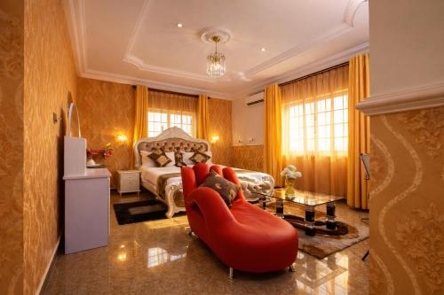 a living room with a red chair and a bed at AG Hotels & Suites in Accra