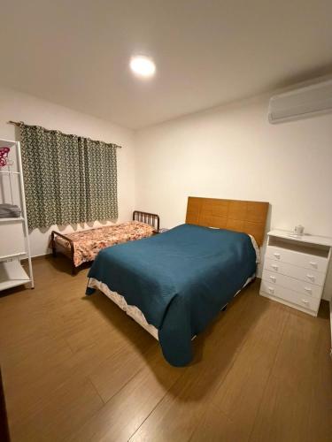 a bedroom with a bed with a blue comforter at Chácara Santo Antonio in Brotas