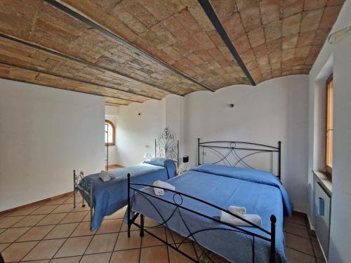 two beds in a bedroom with a wooden ceiling at Affittacamere Fulginiae in Foligno