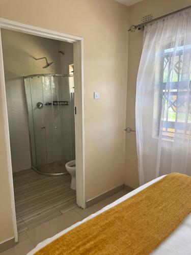 a bathroom with a shower and a toilet and a bed at RosiMug's Homestay in Umtali