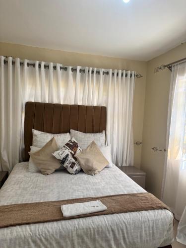a bedroom with a large bed with white sheets and pillows at RosiMug's Homestay in Umtali