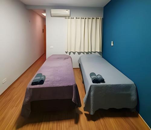 two beds in a room with blue walls and wooden floors at Expo SP, Metrô e Congonhas in São Paulo