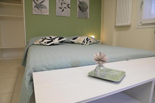 a white bed with a table with a vase on it at Volta B&B Imola in Imola