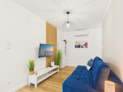 a living room with a blue couch and a tv at Baltic Horizon Klifowa by Solarento in Rewal
