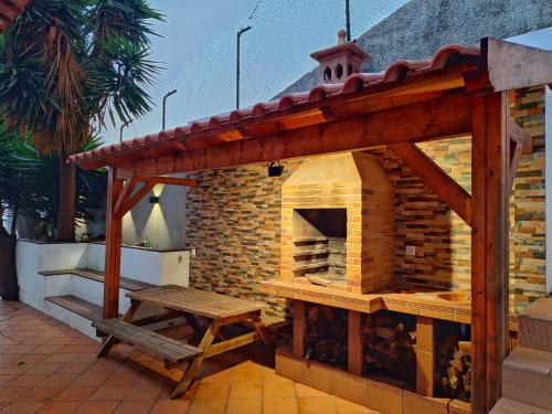 a outdoor pizza oven with a bench on a patio at Skyline Home Funchal in Funchal
