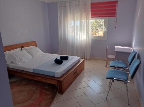 a bedroom with a bed and two chairs and a window at Résidence Mialy in Manankasina