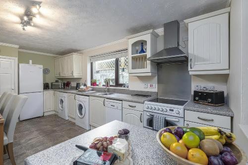 a kitchen with white cabinets and a bowl of fruit on a table at Preswylfa in Cemaes Bay