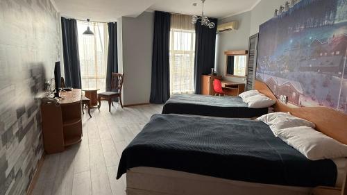a hotel room with two beds and a desk at Three Dolphins Hotel in Aktau