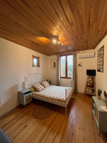 a bedroom with a bed and a wooden ceiling at Les maisons de Gaïa Chambre d'hôte climatisée in Tuchan