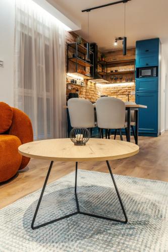 a coffee table in a living room with a table and chairs at Zara Garden Apartment in Novi Sad