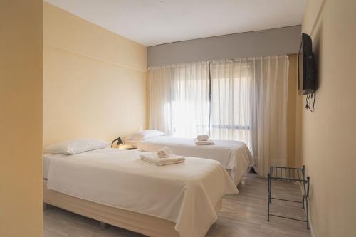 two beds in a room with a window at Rayentray Hostal in Puerto Madryn