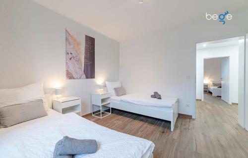 a white bedroom with two beds and a mirror at BEGE APARTMENTS SmileStay in Gelsenkirchen