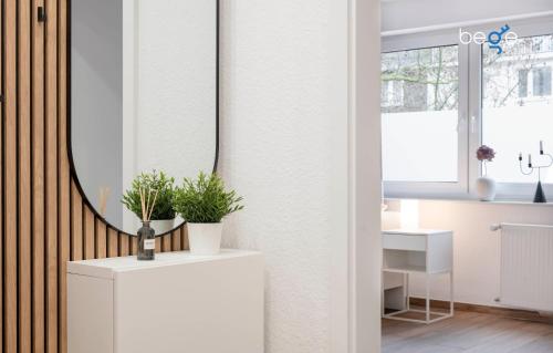 a bathroom with a mirror and a white cabinet with plants at BEGE APARTMENTS SmileStay in Gelsenkirchen