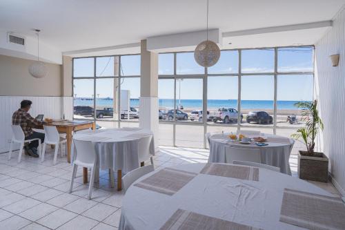 a man sitting at a table in a room with a view of the ocean at Rayentray Hostal in Puerto Madryn