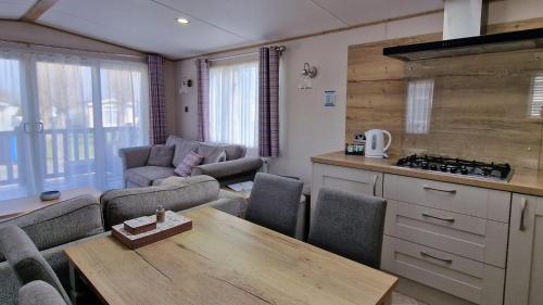 a kitchen and living room with a table and chairs at Rocco Family Retreat, Green Lawns in Selsey
