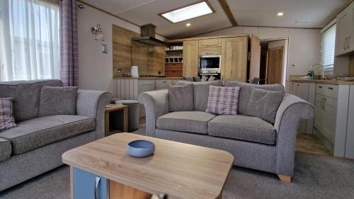 a living room with two couches and a table at Rocco Family Retreat, Green Lawns in Selsey