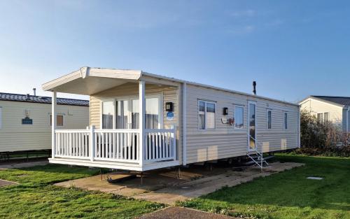 a mobile home with a porch on a yard at Orange Caprice Escape, Church Farm in Pagham